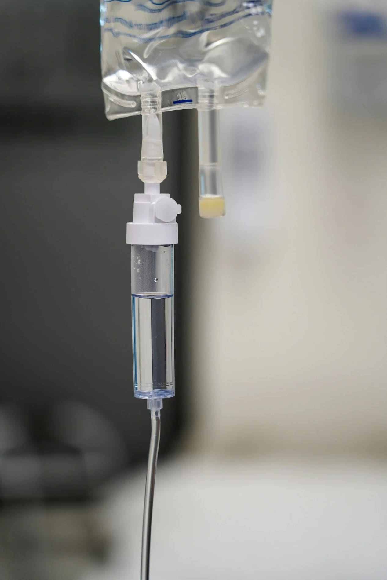 A close-up of a hospital IV drip with clear liquid, hanging from a stand.