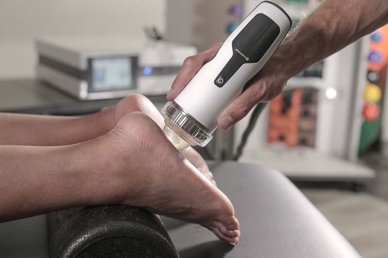 A therapist applying focused shockwave therapy to a patient's foot